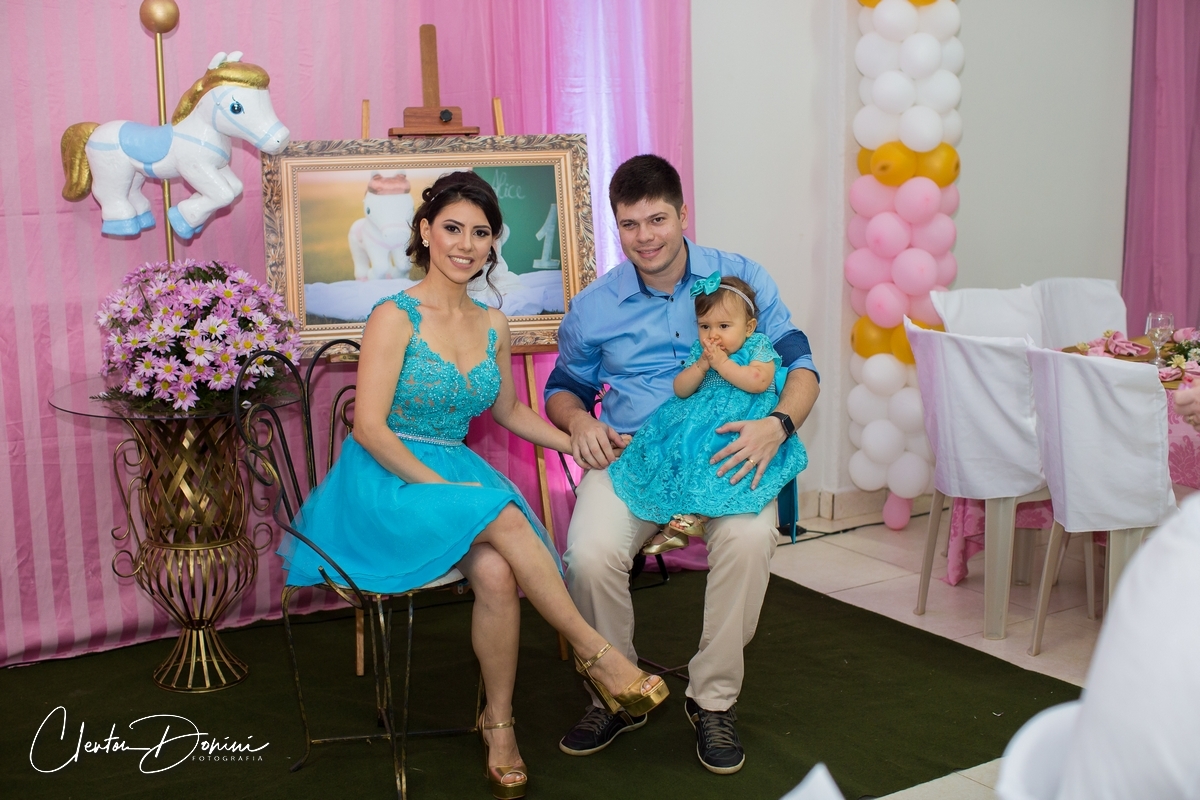 FAMÍLIA SENTADOS EM FRENTE A DECORAÇÃO DE CAVALOS  