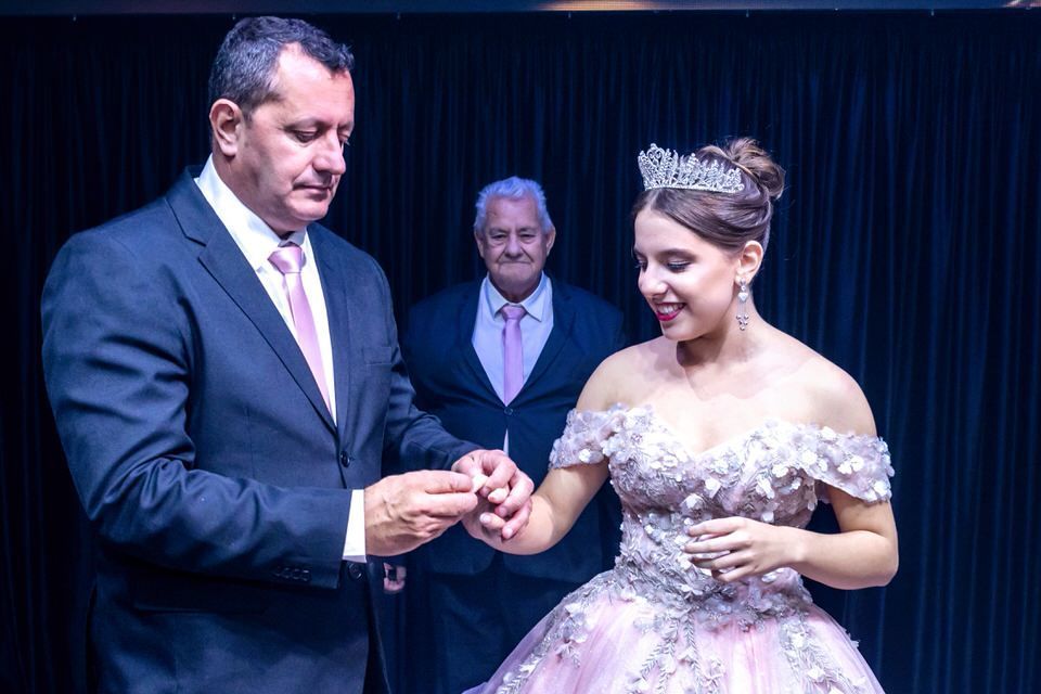 Momento emocionante do pai beijando a mão da debutante Roberta após a entrega do anel. Cobertura fotográfica de festa de 15 anos em SP.