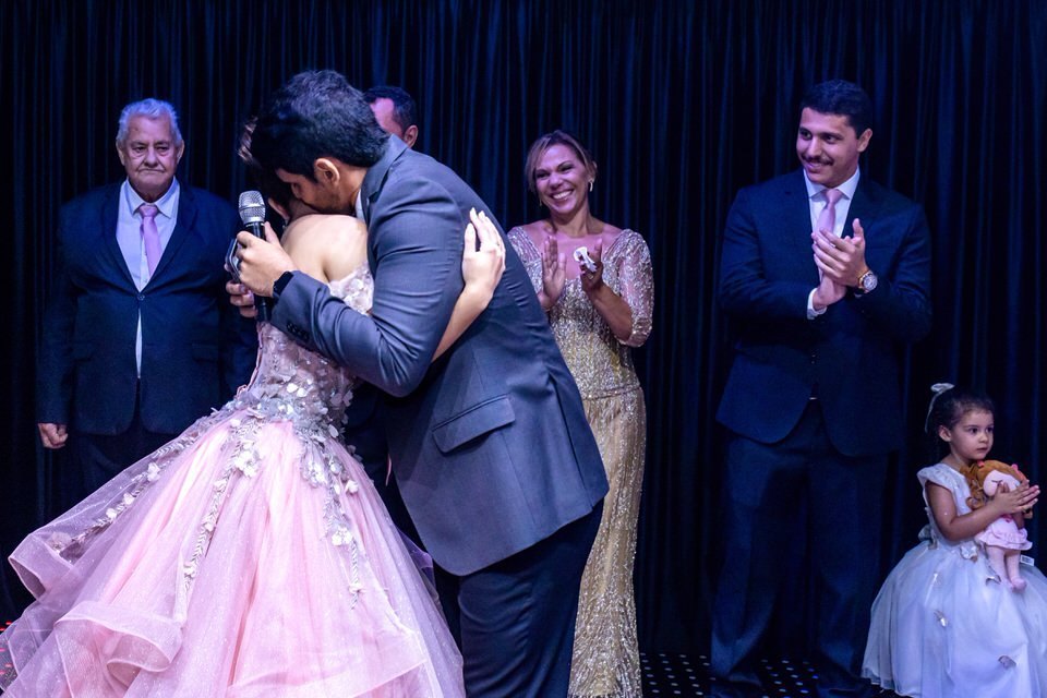 Abraço emocionante após homenagem na festa de 15 anos da debutante Roberta. Cobertura fotográfica de debutante em São Paulo, capturando momentos únicos.