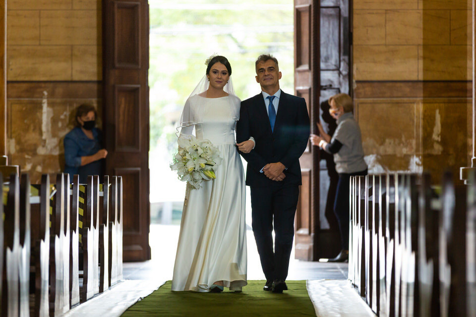 noiva Mariana entrando com o pai na Igreja Matriz Sagrada Família, Noivo esperando a noiva no altar, momento registrado pelo fotógrafo de casamentos John Edgard  em São Bernardo do Campo - SP 
