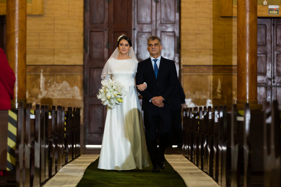 Noiva Mariana com vestido de noiva entrando na igreja, Noivo esperando a noiva no altar, momento registrado pelo fotógrafo de casamentos John Edgard  em São Bernardo do Campo - SP