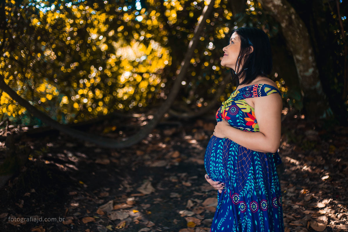 foto da grávida sozinha, com mãos na barriga, olhando para cima com expressão alegre
