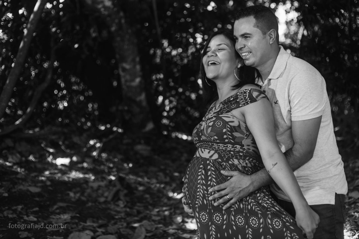 foto marido abraçado com gestante. Os dois estão sorrindo e com ótima expressão