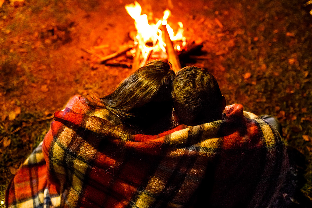 Casal abraçado na fogueira casal no camping