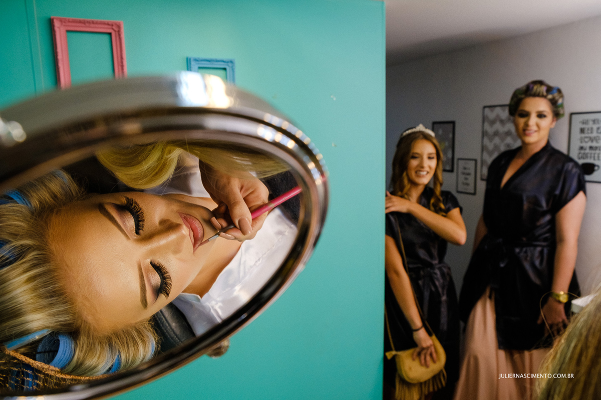 Noiva fazendo maquiagem no espelho no dia de seu making of no salão revolution by Samy makeup em vitória -es.