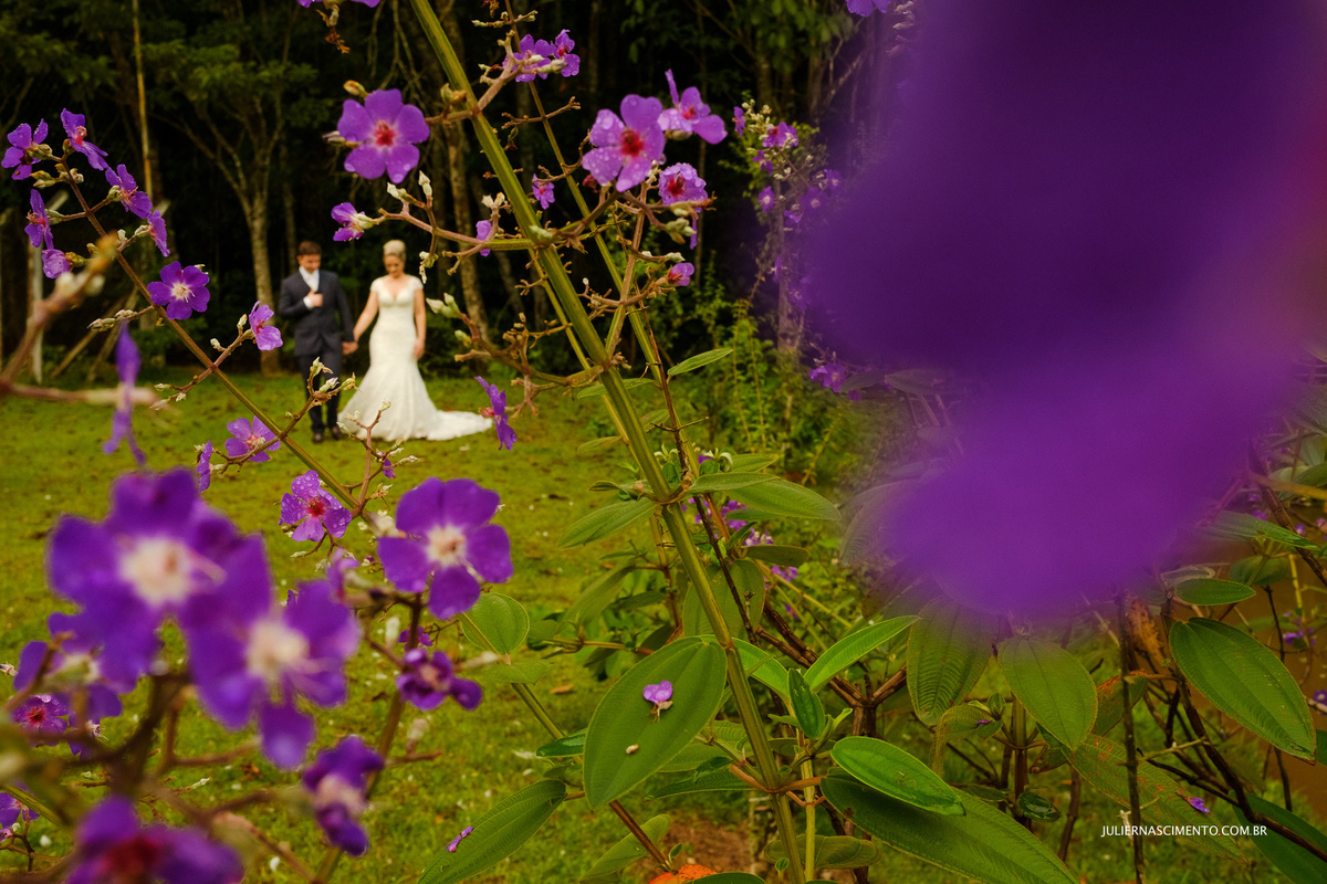 foto de flores roxas com noivos caminhando ao fundo na pousada santa lucia em santa teresa - es