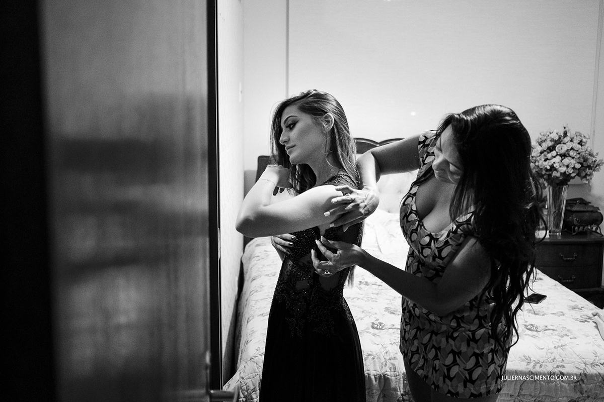 foto de mãe abotoando vestido da filha debutante para a festa de 15 anos