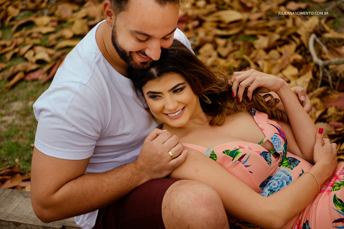 noivo abraçando noiva por trás no meio de folhas secas