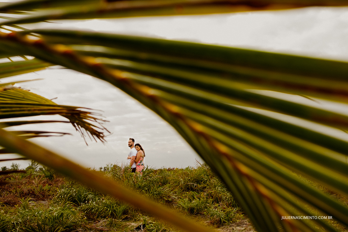 casal entre folhas de coqueiros abraçados