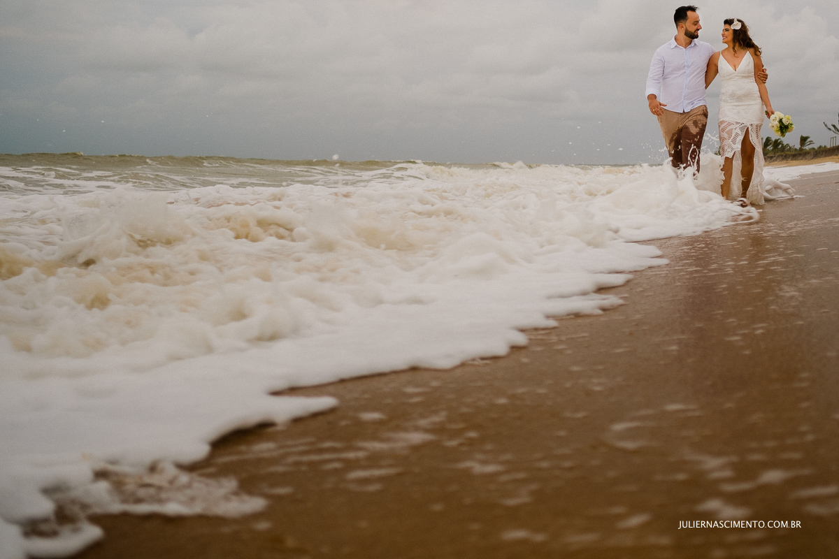 noivos caminhando a beira mar na praia em nova viçosa na Bahia