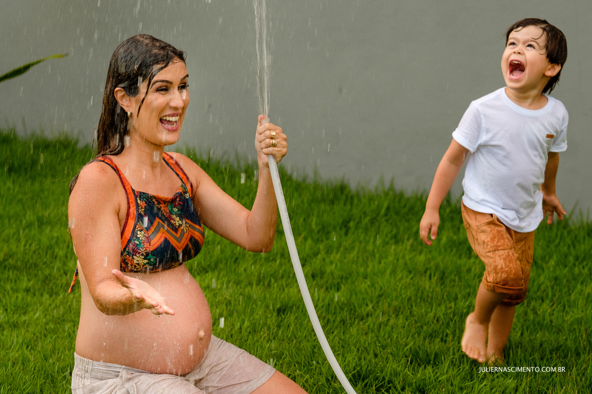 foto de mãe gestante e seu filho brincando com água