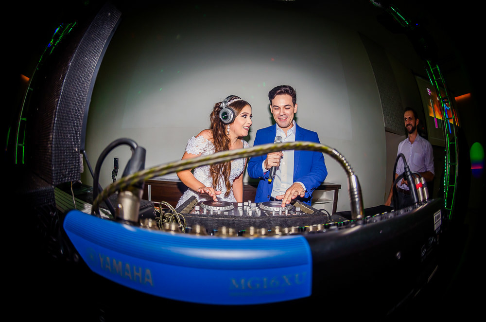 Fotografia da recepção ou festa de casamento dos noivos na mesa do DJ sorrindo no espaço de eventos em Maringá, PR