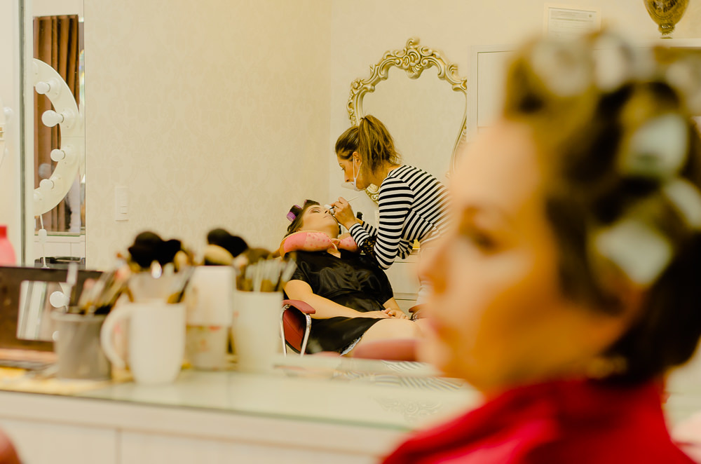 Fotografia de making of da noiva com sua mãe no salão de beleza no dia da noiva arrumando o cabelo e fazendo a maquiagem para o casamento em Maringá PR