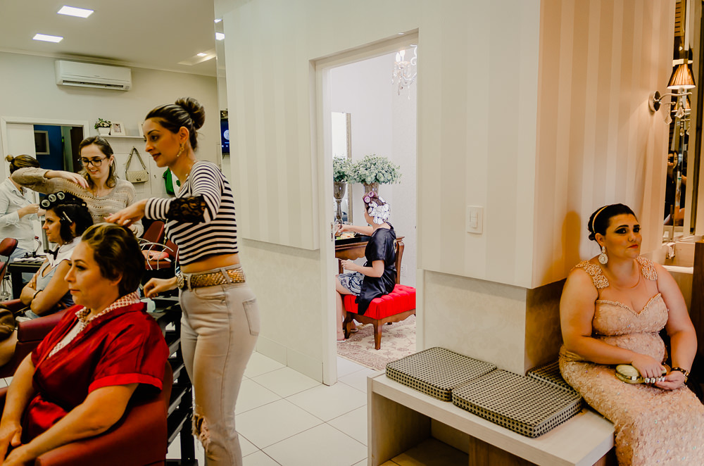 Fotografia na noiva no making of no dia do casamento no salão de beleza no dia da noiva com sua cunhada e mãe arrumando o cabelo em Maringá PR