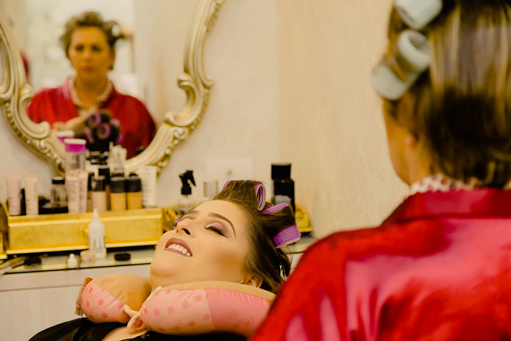 Fotografia de making of da noiva com sua mãe no salão de beleza no dia da noiva arrumando o cabelo e fazendo a maquiagem para o casamento em Maringá PR