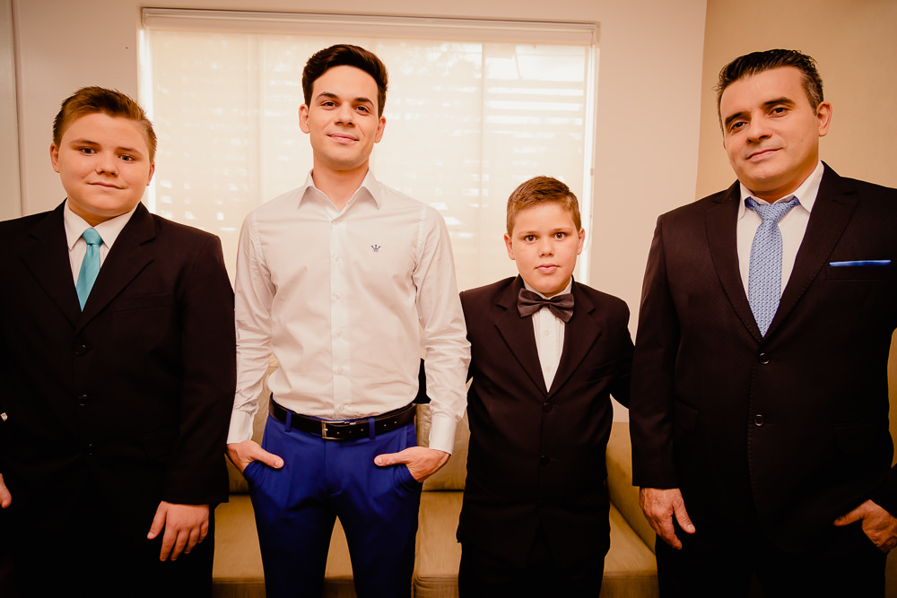 Fotografia do Noivo no dia do casamento no making of do noivo de calça azul e camisa branca junto com seu pai e dois irmãos em Maringá PR