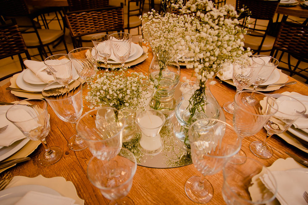 Fotografia da decoração do dia do casamento da mesa de jantar com os pratos, talheres, taças e flores sobre a mesa no salão de festas em Maringá PR