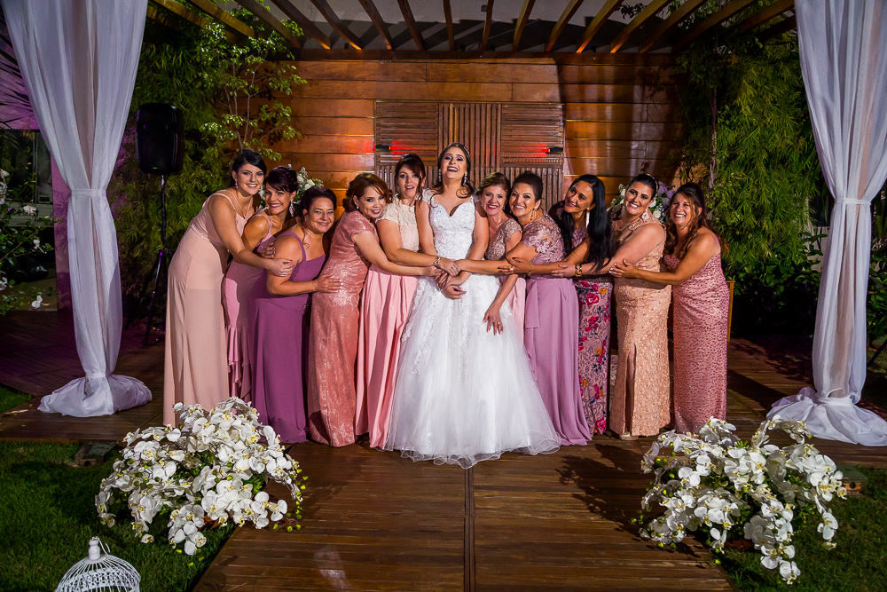 Fotografia da recepção ou festa de casamento no espaço a céu aberto da noiva usando vestido de noiva branco e longo sorrindo e as madrinhas de casamento de vestidos de tons de rosa no espaço de eventos em Maringá, PR