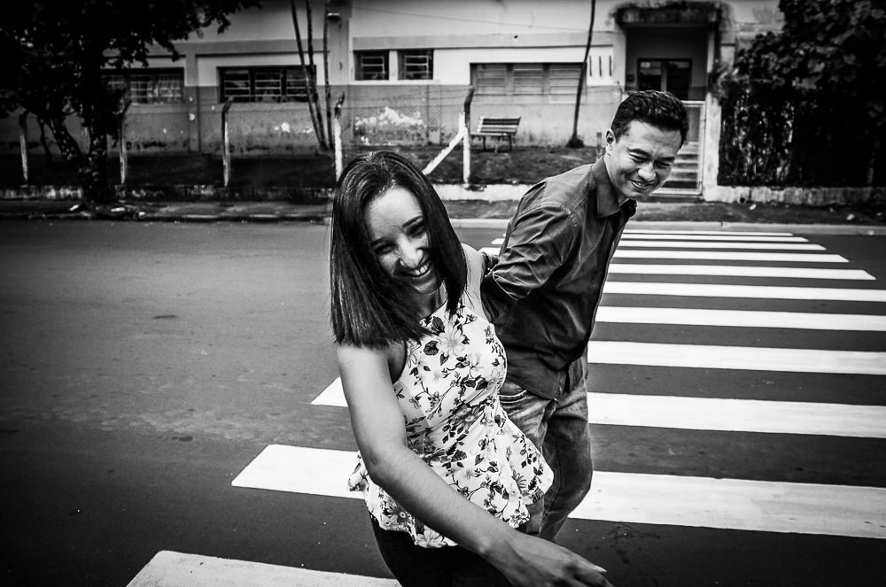 Casal de noivos sorrindo andando na rua na faixa de pedestres em Araçatuba, SP