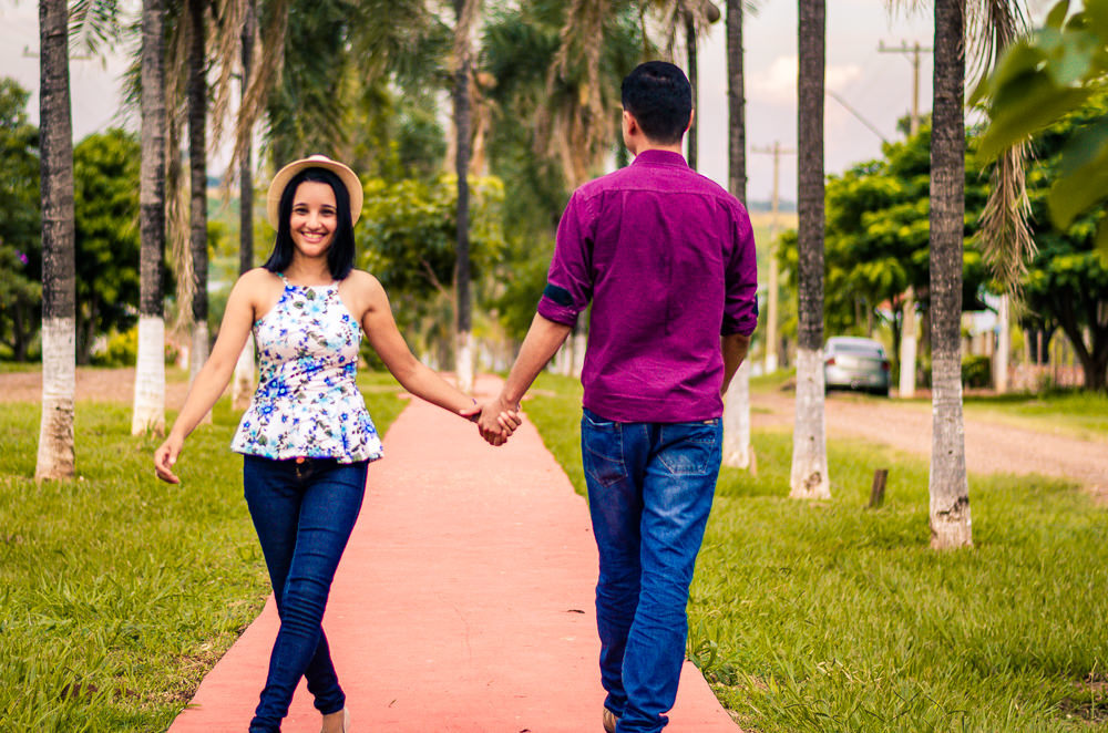 Fotografia do casal de noivos no ensaio pre casamento ou wedding. Estão caminhando, ela de frente e ele de costas e de mãos dadas em Araçatuba, SP