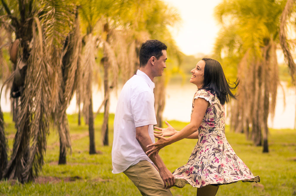 Fotografia no campo com sol e palmeiras ao fundo e o rio Tietê do noivo e da noiva no ensaio pre casamento ou wedding em Araçatuba, SP