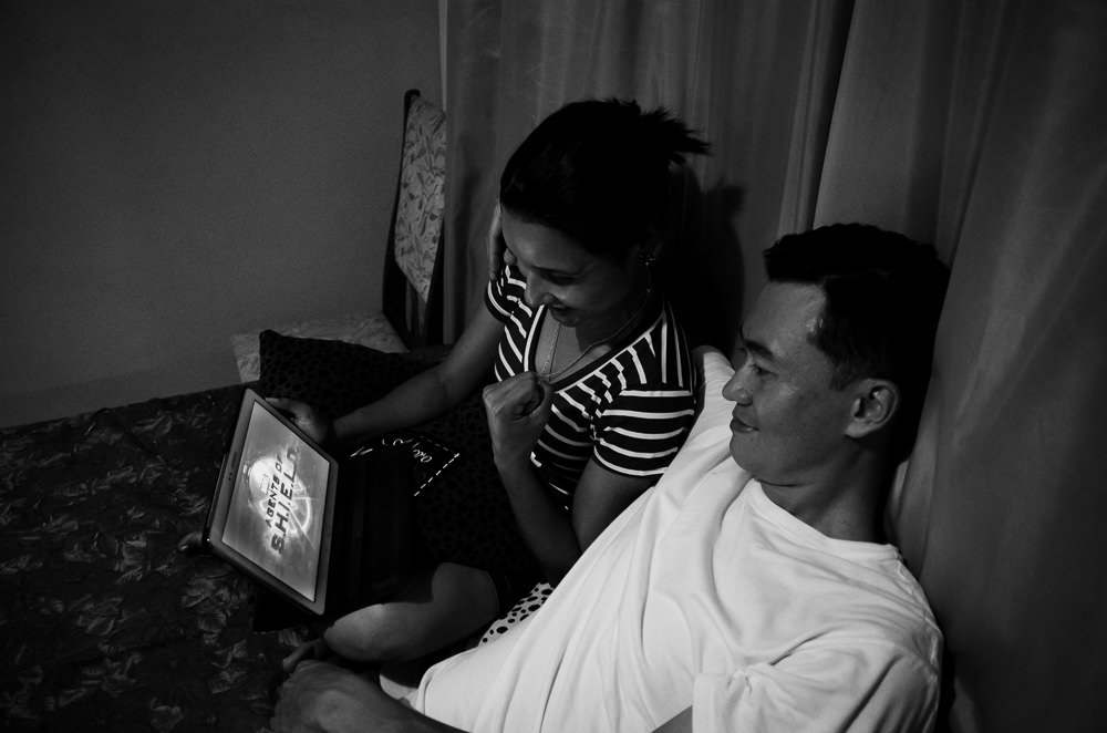 Fotografia no ensaio pre casamento ou wedding do casal de noivos assistindo a uma série da Marvel, Agentes da SHIELD juntos em um tablet em Araçatuba, SP