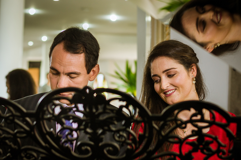 Foto do ensaio pre wedding, casamento, do casal de noivos. Estão ao piano de cauda, o noivo de traje completo, terno e gravata e a noiva de vestido vermelho no Hotel Capo Zorial no Recanto do Maestro em São João do Polêsine, RS, próximo de Santa Maria, RS