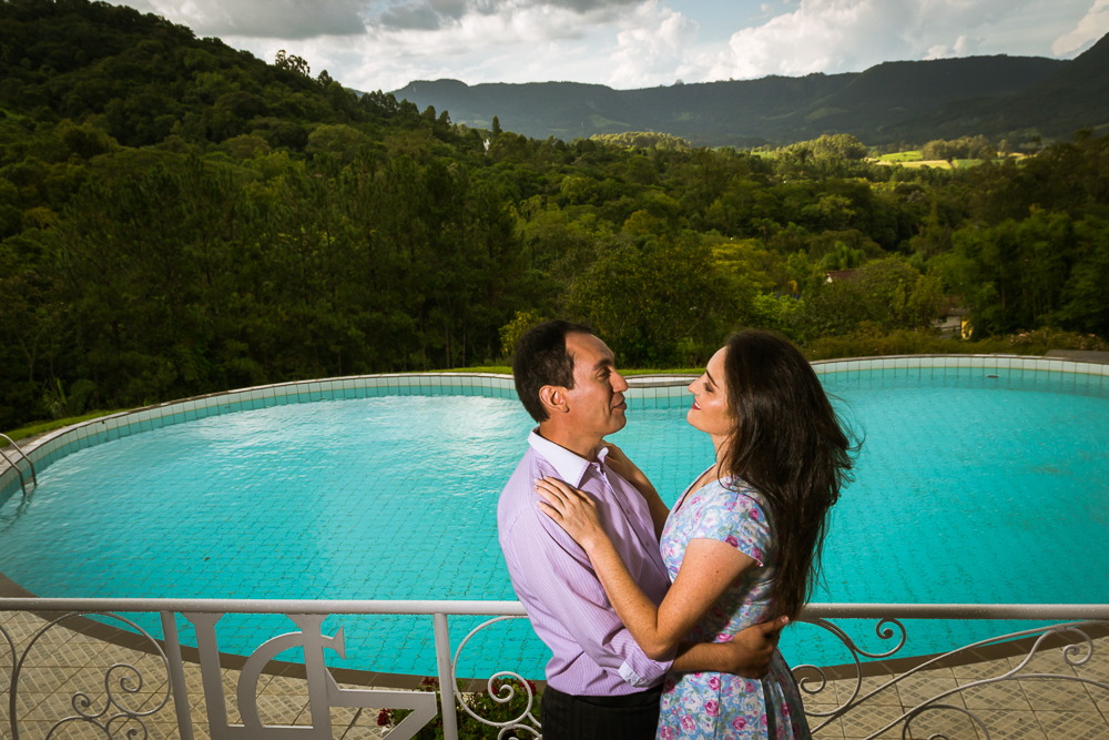 Foto do ensaio pre wedding, casamento, do casal de noivos. ao ar livre, o noivo de terno, a noiva de vestido no Hotel Capo Zorial com piscina e monte ao fundo no Recanto do Maestro em São João do Polêsine, RS, próximo de Santa Maria, RS