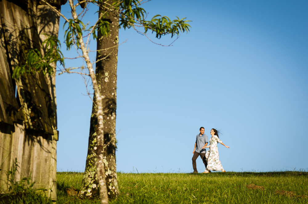 Foto do ensaio pre wedding, casamento, do casal ao ar livre com sol e céu azul no Hotel Capo Zorial com piscina e monte ao fundo no Recanto do Maestro em São João do Polêsine, RS, próximo de Santa Maria, RS