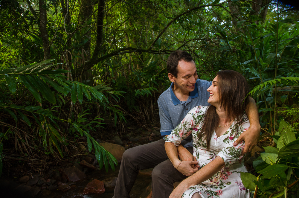 Foto do ensaio pre wedding, casamento, do casal ao ar livre no riacho com cascalhos na vegetação verde no Hotel Capo Zorial com piscina e monte ao fundo no Recanto do Maestro em São João do Polêsine, RS, próximo de Santa Maria, RS