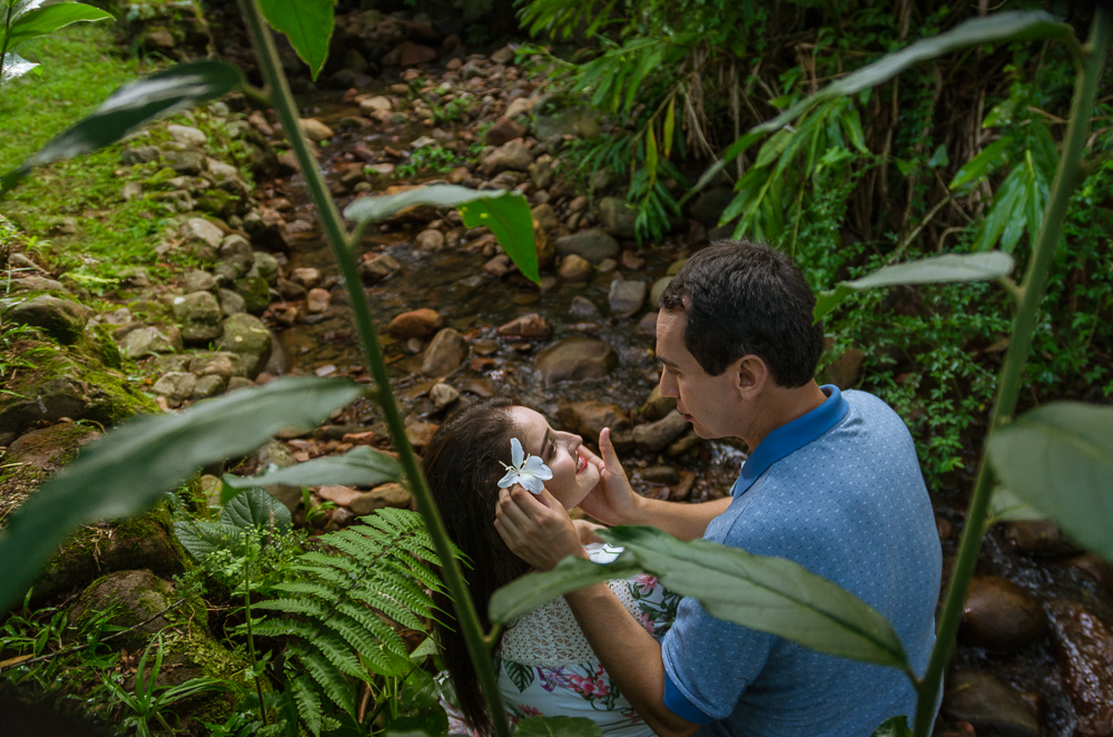 Foto do ensaio pre wedding, casamento, do casal ao ar livre no riacho com cascalhos na vegetação verde no Hotel Capo Zorial com piscina e monte ao fundo no Recanto do Maestro em São João do Polêsine, RS, próximo de Santa Maria, RS