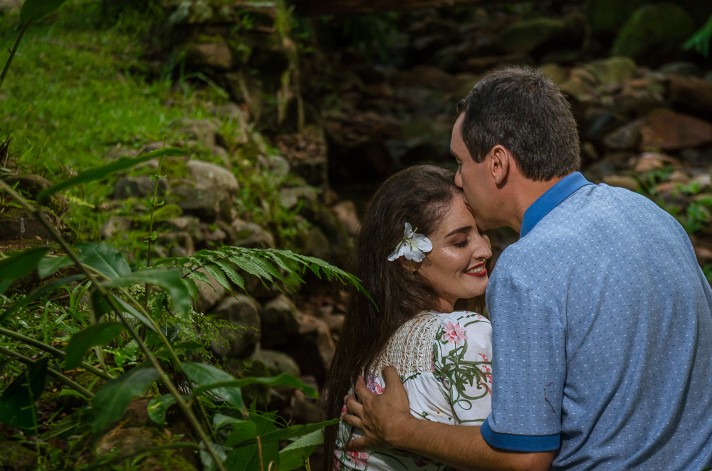 Foto do ensaio pre wedding, casamento, do casal ao ar livre no riacho com cascalhos na vegetação verde no Hotel Capo Zorial com piscina e monte ao fundo no Recanto do Maestro em São João do Polêsine, RS, próximo de Santa Maria, RS