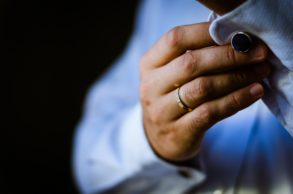 Foto do ensaio de making of do noivo no quarto fazendo os preparativos para o casamento. Detalhe das abotoaduras em Restinga Seca, RS 