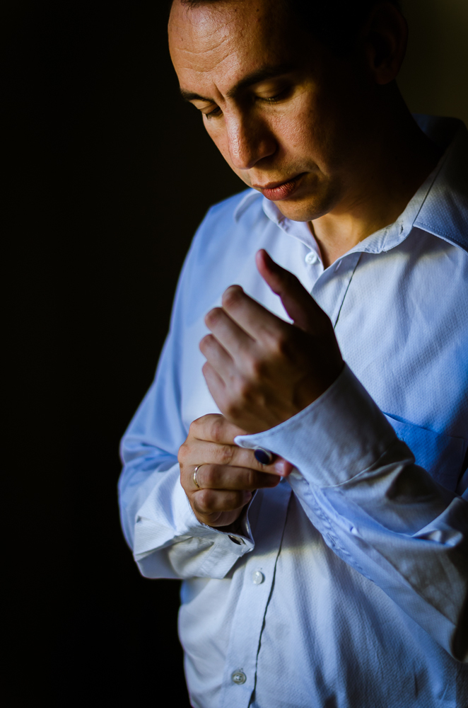 Foto do ensaio de making of do noivo no quarto fazendo os preparativos para o casamento. Corpo inteiro, e detalhe das abotoaduras em Restinga Seca, RS 