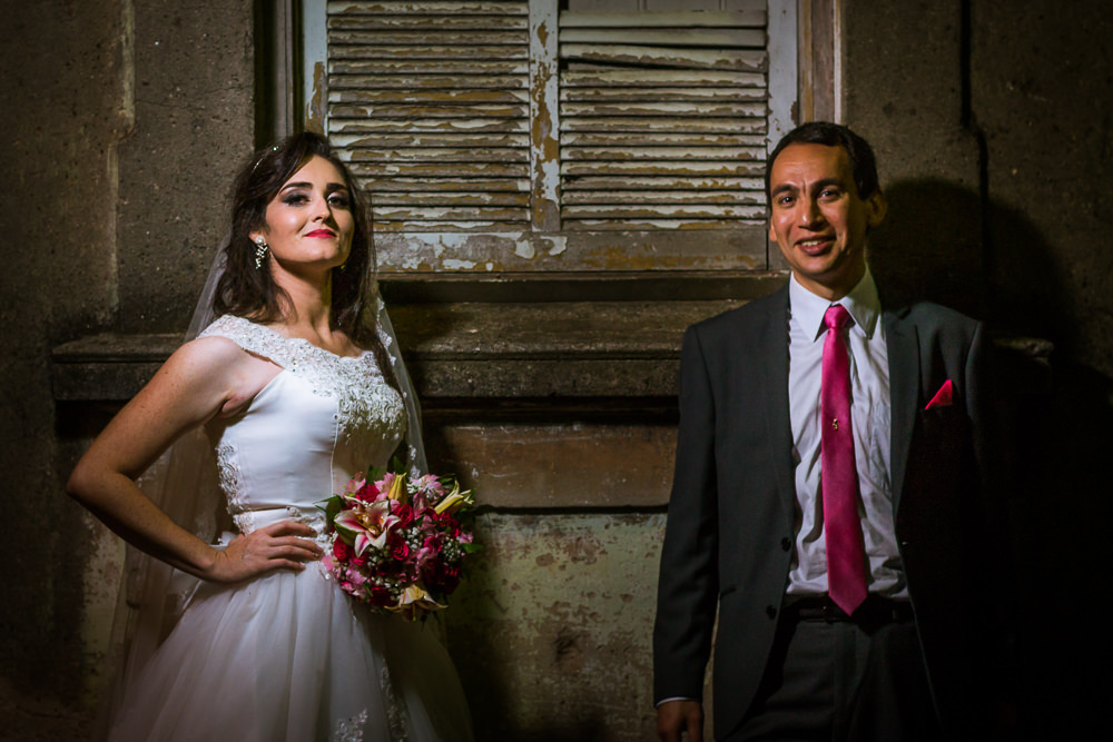 Foto do retrato no ensaio fotográfico no dia do casamento do casamento de noivos. Ele de terno,, gravata e ela de vestido de noiva branco, na Vila Belga em Santa Maria, RS