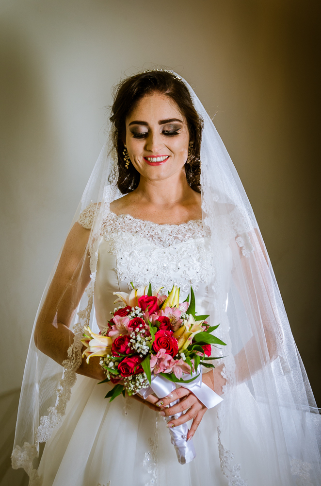 Foto do ensaio making ok na noiva no salão de beleza Centher Hair no dia da noiva fazendo o penteado e maquiagem. Retrato da noiva pronta sorrindo, de batom, brincos, véu,  vestido longo brando e bouquet, buquê. Em Santa Maria, RS