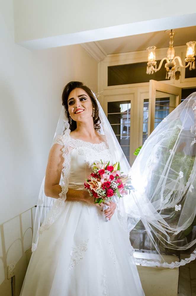 Foto do ensaio making ok na noiva no salão de beleza Centher Hair no dia da noiva fazendo o penteado e maquiagem. Retrato da noiva pronta sorrindo, de batom, brincos, véu,  vestido longo brando e bouquet, buquê. Em Santa Maria, RS