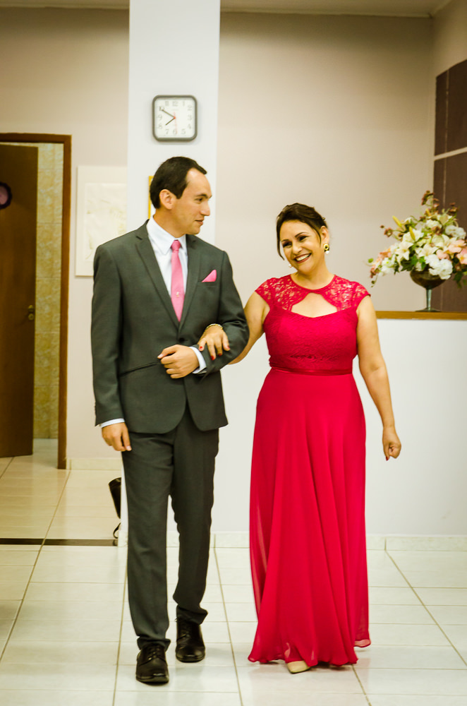 Foto da cerimônia de casamento no Salão do Reino das Testemunhas de Jeová, JW, em Santa Maria, RS. O noivo de terno, gravata e lenço com a mãe do noivo de vestido longo vermelho.