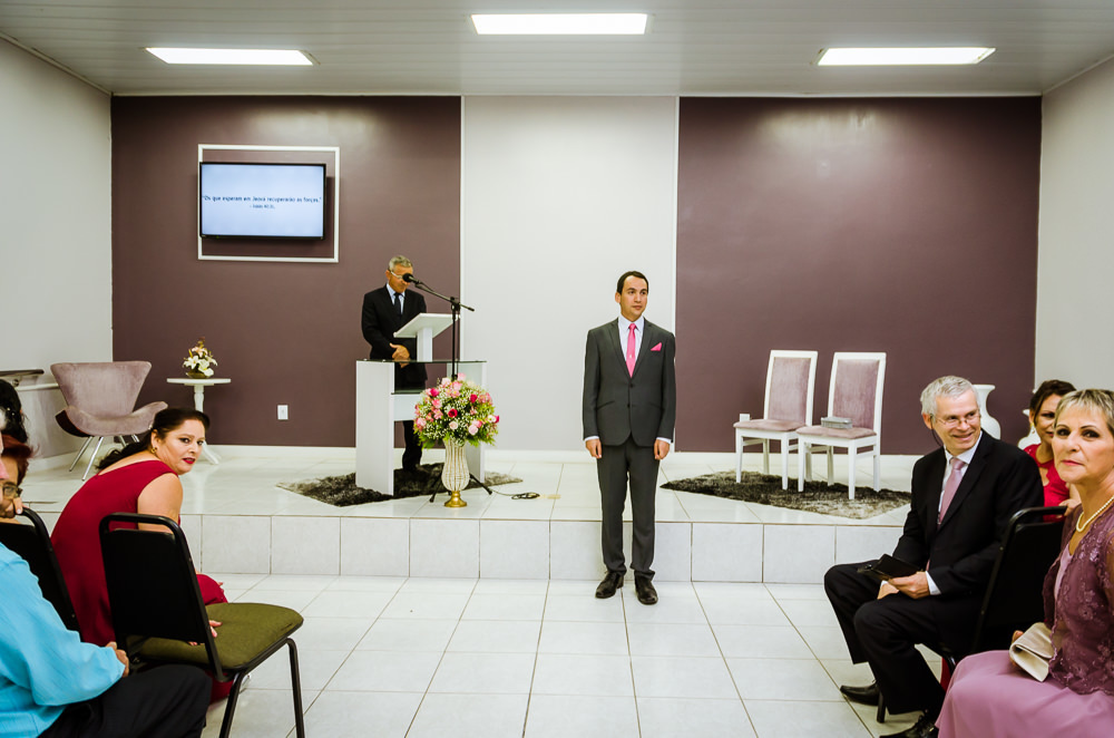Foto da cerimônia de casamento no Salão do Reino das Testemunhas de Jeová, JW, em Santa Maria, RS. Entrada da noiva. Convidados e noivo olham com alegria a entrada da noiva.