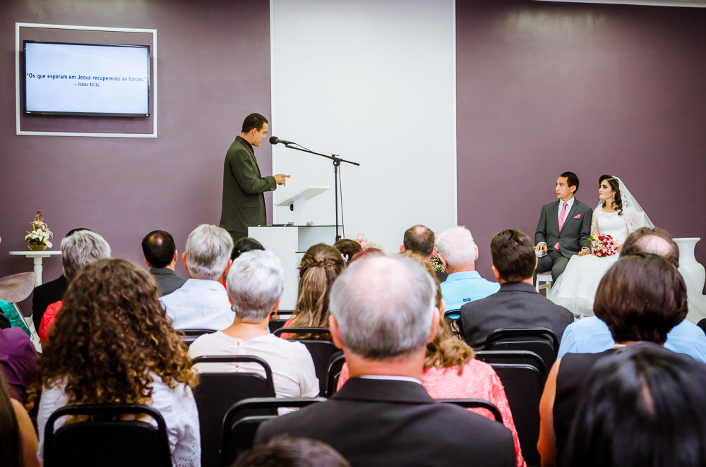 Foto da cerimônia de casamento no Salão do Reino das Testemunhas de Jeová, JW, em Santa Maria, RS. Convidados, noivos no paldo e orador do discurso de casamento.