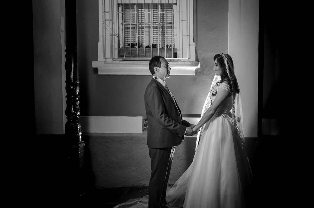 Foto do retrato no ensaio fotográfico no dia do casamento dos noivos. Ele de terno, gravata e ela de vestido de noiva branco, na Vila Belga em Santa Maria, RS