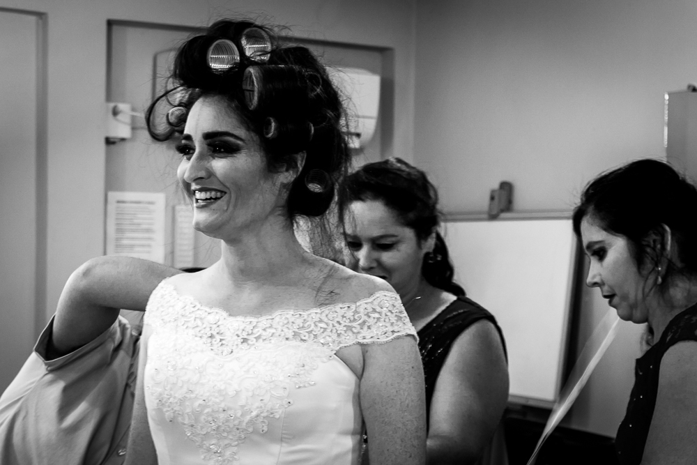 Foto do ensaio making ok na noiva no salão de beleza Centher Hair no dia da noiva fazendo o penteado e maquiagem. Ja está com o vestido de noiva branco, a mãe e tia da noiva ajuda a se vestir. Em Santa Maria, RS