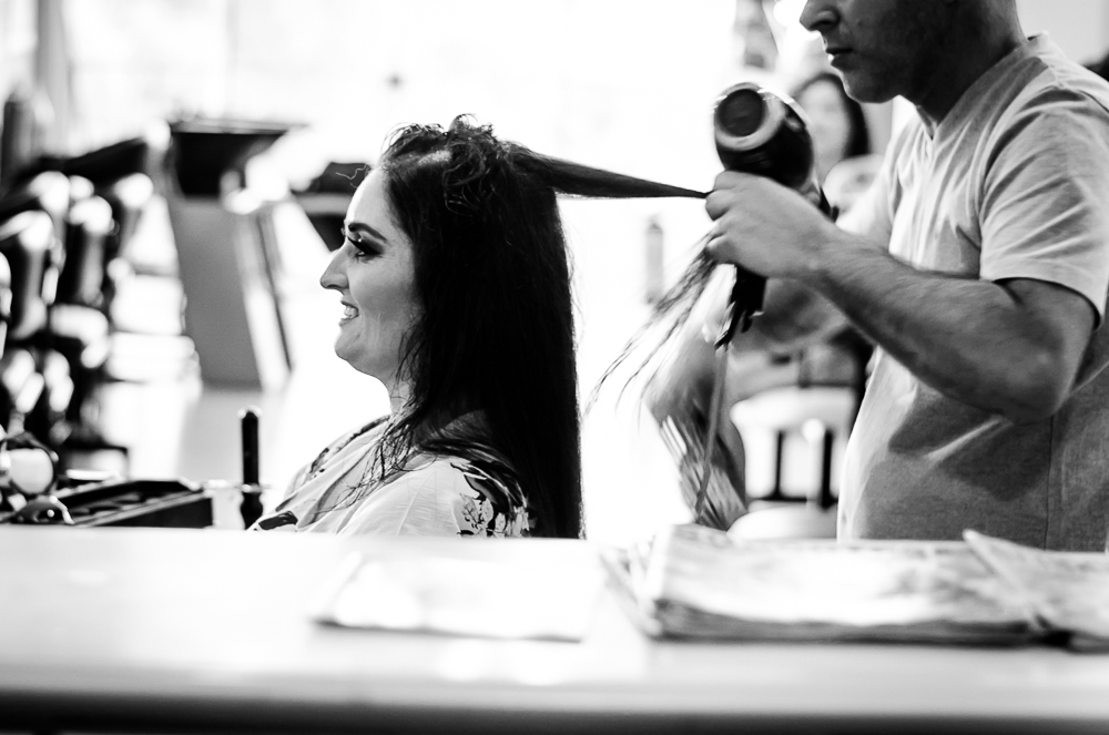 Foto do ensaio making ok na noiva no salão de beleza Centher Hair no dia da noiva fazendo o penteado e maquiagem. Ela sorri enquanto o cabeleireiro faz o penteado. Em Santa Maria, RS