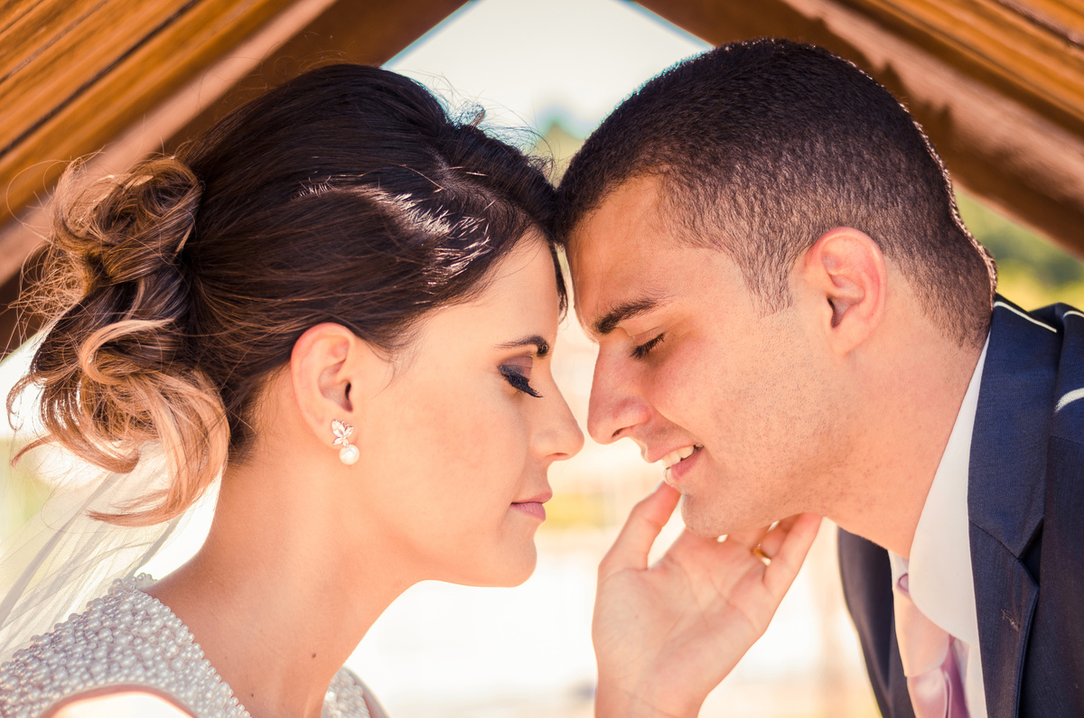 Foto do ensaio após a cerimônia de casamento dos noivos. A noiva está de vestido de noiva branco e véu com o bouquet, buquê, e o noivo de terno azul e gravata rosa em Cajamar, São Paulo