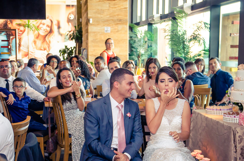 Foto dos noivos chegando a recepção por adesão no Anhanguera Parque Shopping, a noiva está de vestido brando e véu com o bouquet, buquê e o noivo de terno azul e gravata rosa em Cajamar, São Paulo
