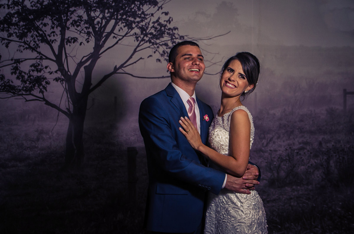 Retrato dos noivos chegando a recepção por adesão no Anhanguera Parque Shopping, a noiva está de vestido brando e véu com o bouquet, buquê e o noivo de terno azul e gravata rosa em Cajamar, São Paulo