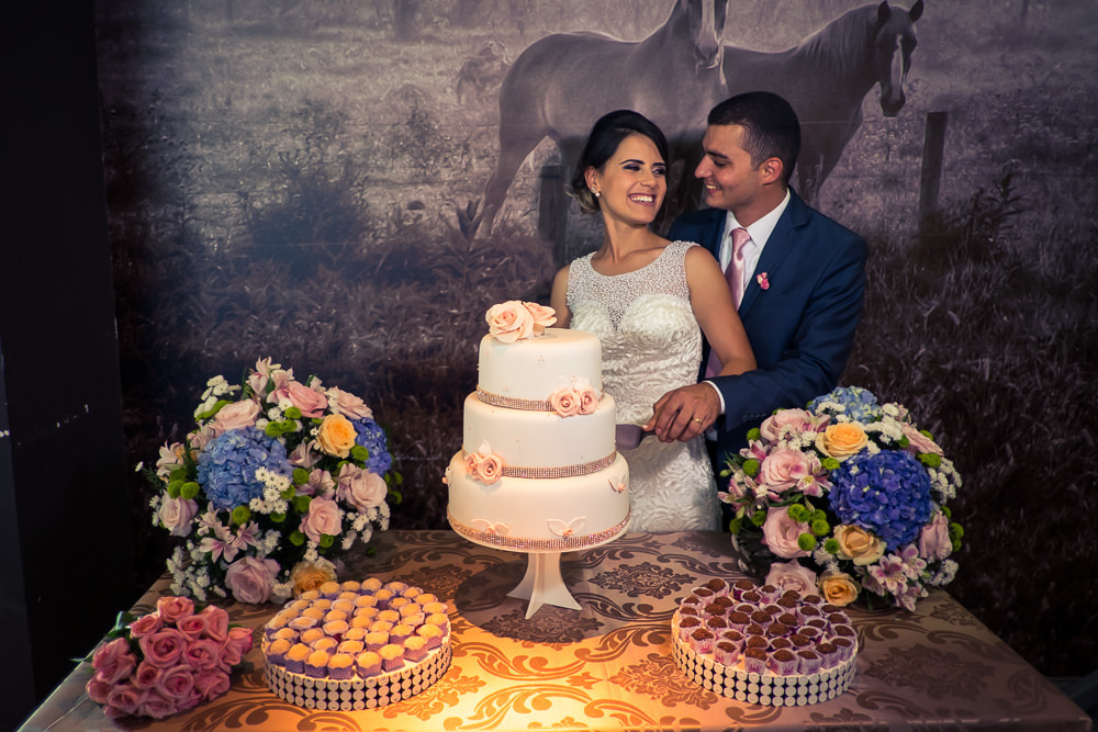 Retrato dos noivos chegando a recepção por adesão no Anhanguera Parque Shopping, a noiva está de vestido brando e véu com o bouquet, buquê e o noivo de terno azul e gravata rosa em Cajamar, São Paulo