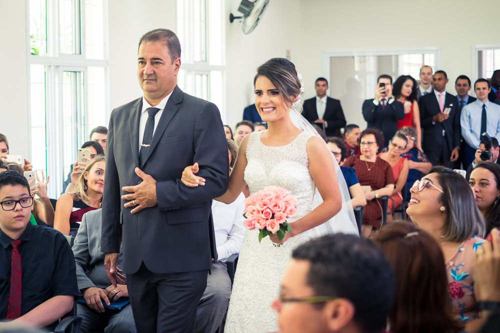 Fotografia da noiva de vestido branco na entrada da noiva para cerimônia de casamento com o pai em Cajamar, São Paulo