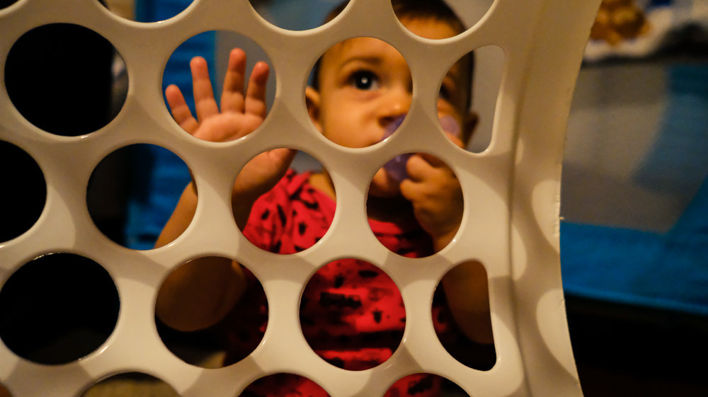 Fotografia documental de Família, Criança bebê brincando com dentro de um cesto de roupas. Foto colorida em Barueri, SP