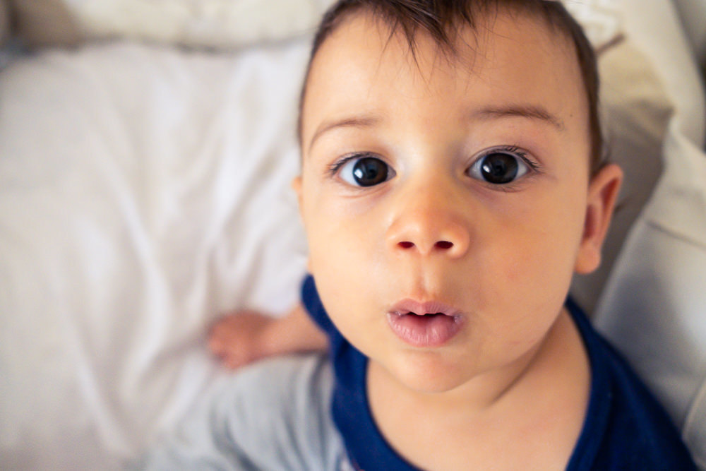 Fotografia Documental de Família. Foto da rotina da família com seu filho criança bebê, mostrando a essência a história da família.  Foto em Barueri, SP. Bebê criança dentro do berço olhando para a camera